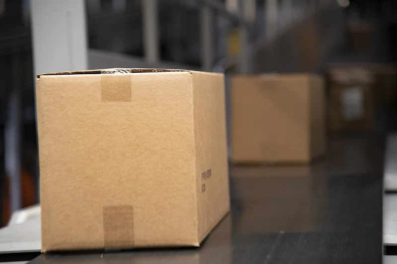 A cardboard box on a conveyor belt in a blurred warehouse setting