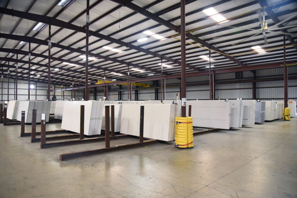 Interior view of a warehouse showcasing large white slabs arranged in organized rows, illustrating efficient inventory management.